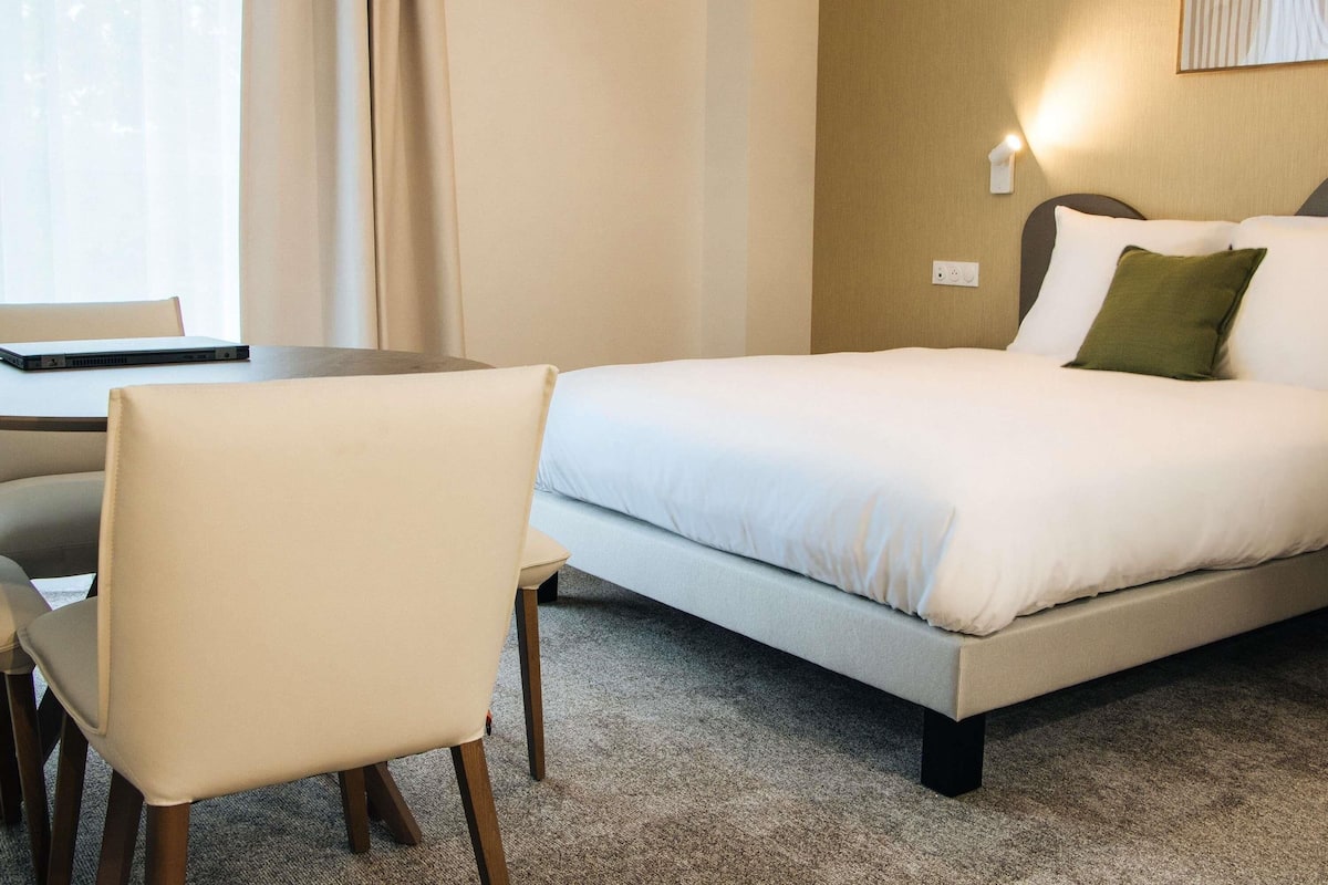 A hotel room with a bed, a desk, and a chair.