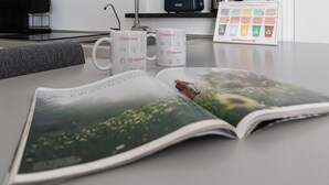 A magazine open on a table with a coffee cup and a framed recycling guide. - Italianway Easy - Ticinese 83, 15 min to Linate (Milan)