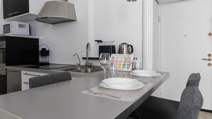 A modern kitchen with a central island, stainless steel appliances, and a dining area with a table set for two. - Italianway Easy - Ticinese 83, 15 min to Linate (Milan)