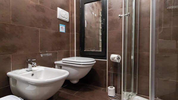 Un baño moderno con bidé, inodoro y ducha con cerramiento de vidrio.