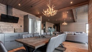 Une cuisine moderne avec une table à manger en bois, des chaises noires et un lustre.