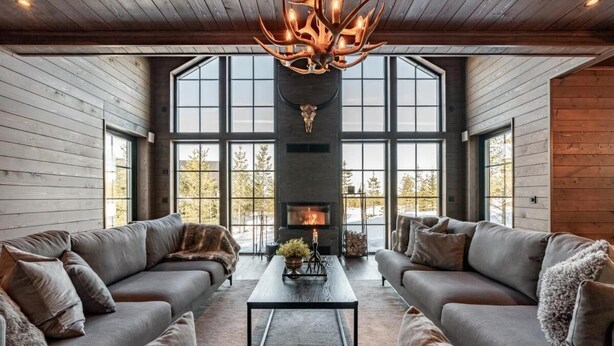 Un salon moderne doté d’une cheminée, de grandes fenêtres et d’un plafond en bois.