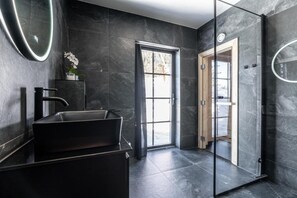 A modern bathroom with a black sink, a mirror, and a glass shower enclosure. - Idre Sky Mountain Lodge- Ski in Ski out (Idre)