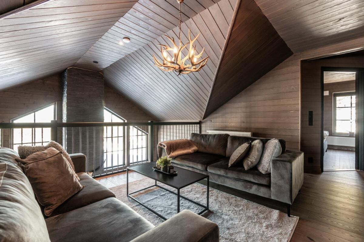 Un loft spacieux avec un plafond en pente, un grand ensemble de canapés, une table basse et un lustre.