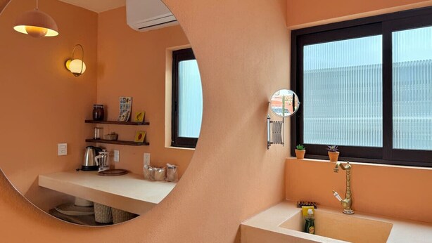 Une cuisine moderne avec un miroir rond, une fenêtre et un évier.
