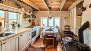 Une cuisine avec des meubles de rangement en bois, une cuisinière et un coin repas comprenant une table et des chaises.