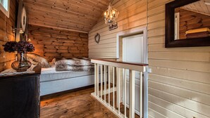 Un intérieur en bois avec un banc, un lustre et une porte blanche.