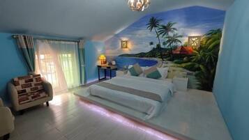 A bedroom with a bed, a chair, a nightstand, and a mural of a tropical beach scene.