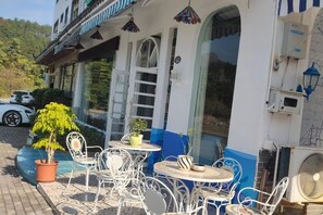 A building with outdoor seating and a white and blue facade. - Kyushu Chain Inn (Observation Store) (Renhua)