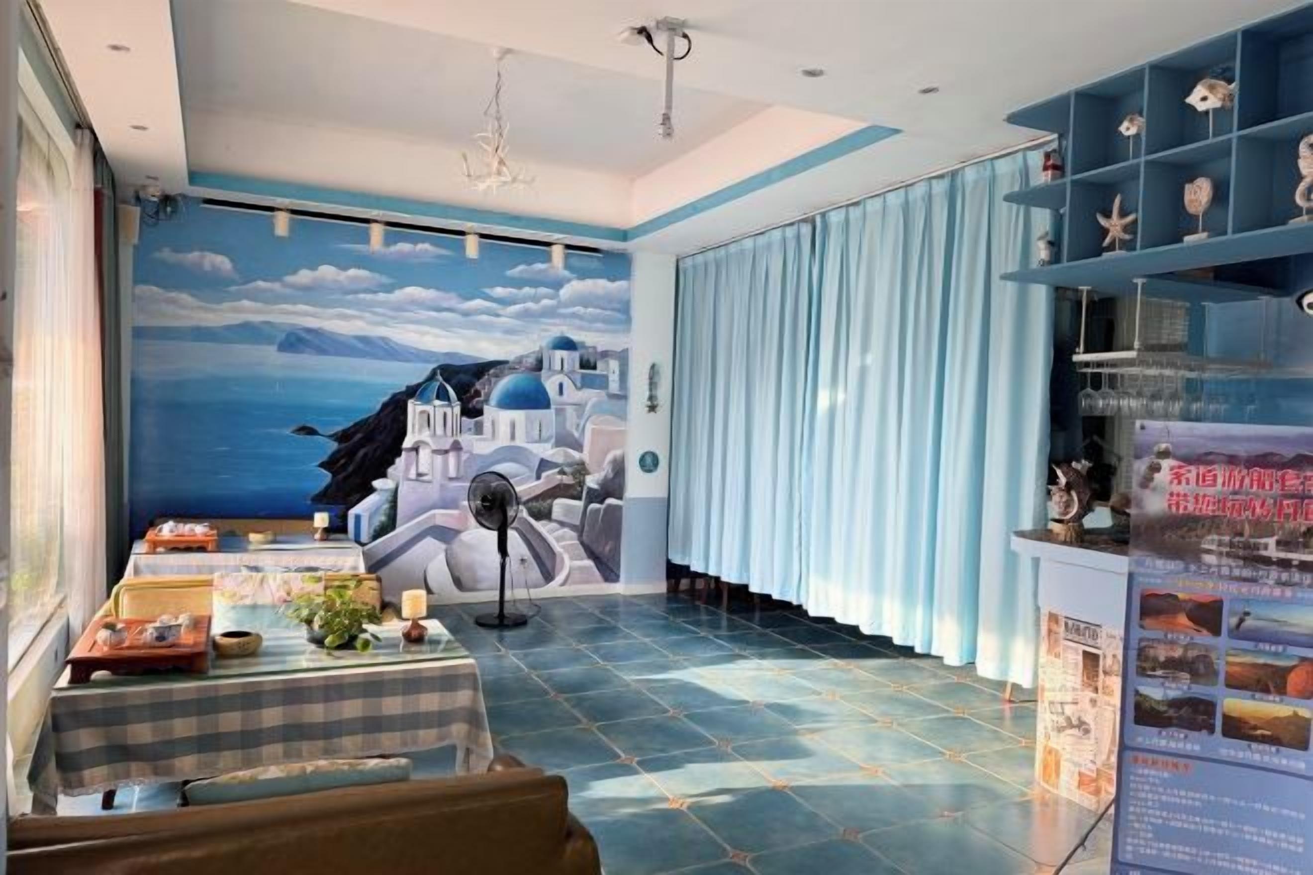 A room with a mural of a coastal scene, a dining area with a table, and a blue-striped wall.