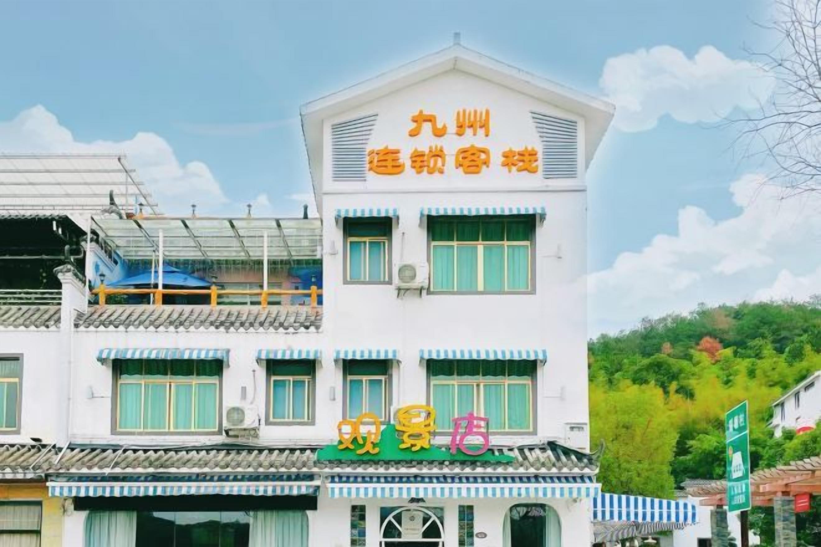 A multi-story building with a traditional architectural style, featuring a prominent sign with Chinese characters, a balcony on the upper floor, and a storefront with a green awning.