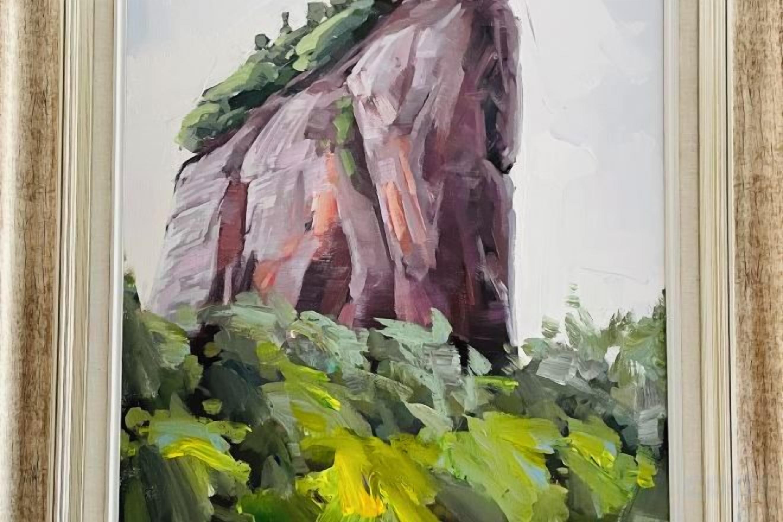 A framed painting of a rock formation with foliage.