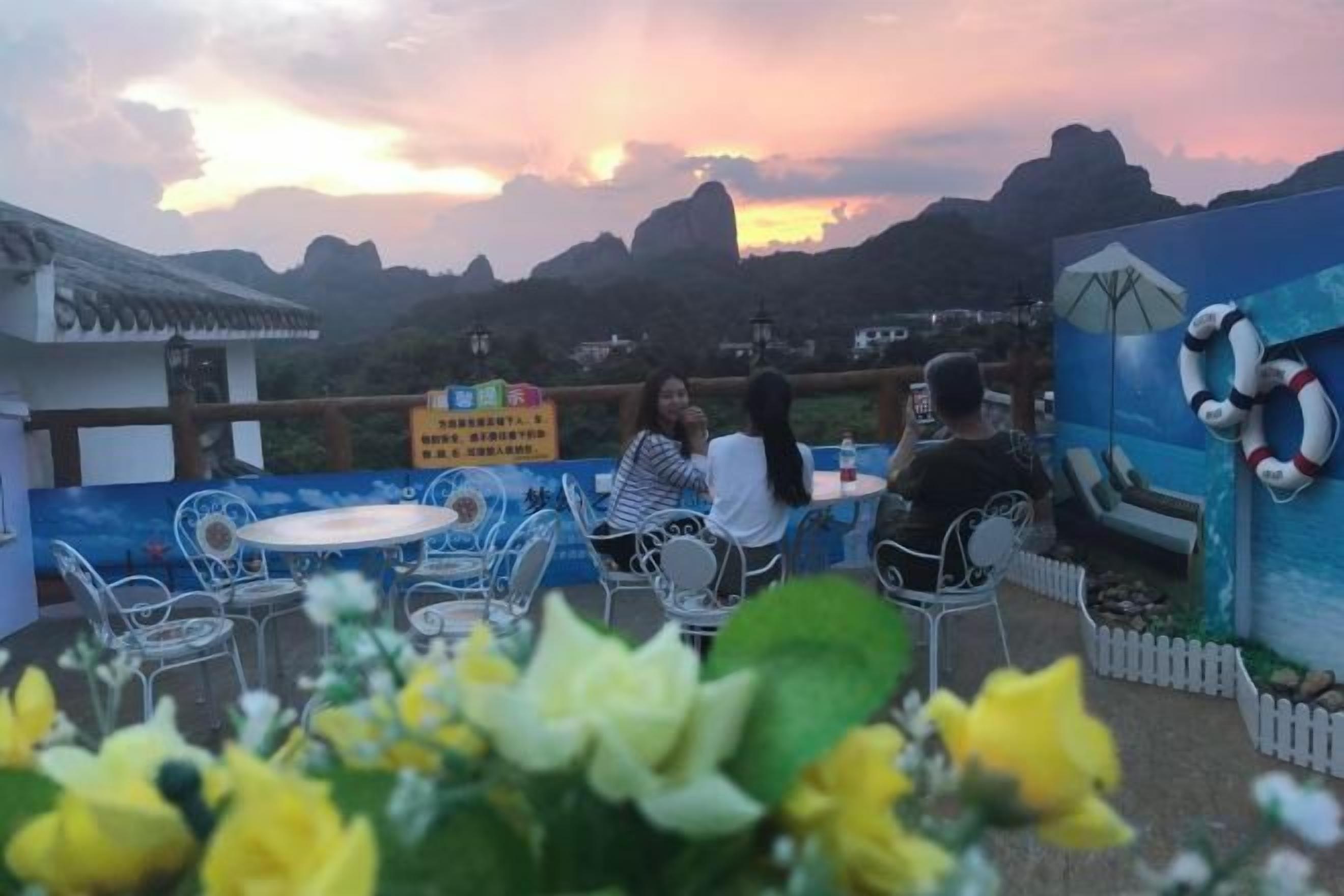 An outdoor seating area with tables and chairs, overlooking a mountainous landscape.