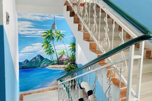 Una escalera con un mural que muestra una escena de playa tropical.