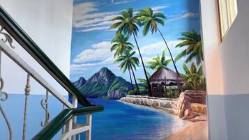 A mural of a tropical beach scene with palm trees and mountains.