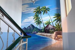 A mural of a tropical beach scene with palm trees and mountains. - Kyushu Chain Inn (Observation Store) (Renhua)