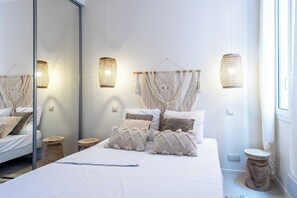 A modern bedroom with a large bed, macramé wall hangings, and a mirror. - Modern Apartment -1bdr/4p - 300m From the Beach (Antibes)