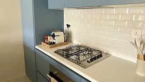 A modern kitchen with blue cabinets, a white countertop, and a gas stove. - Aladdin Chalets - 2.5 Bedrooms (Aqaba)