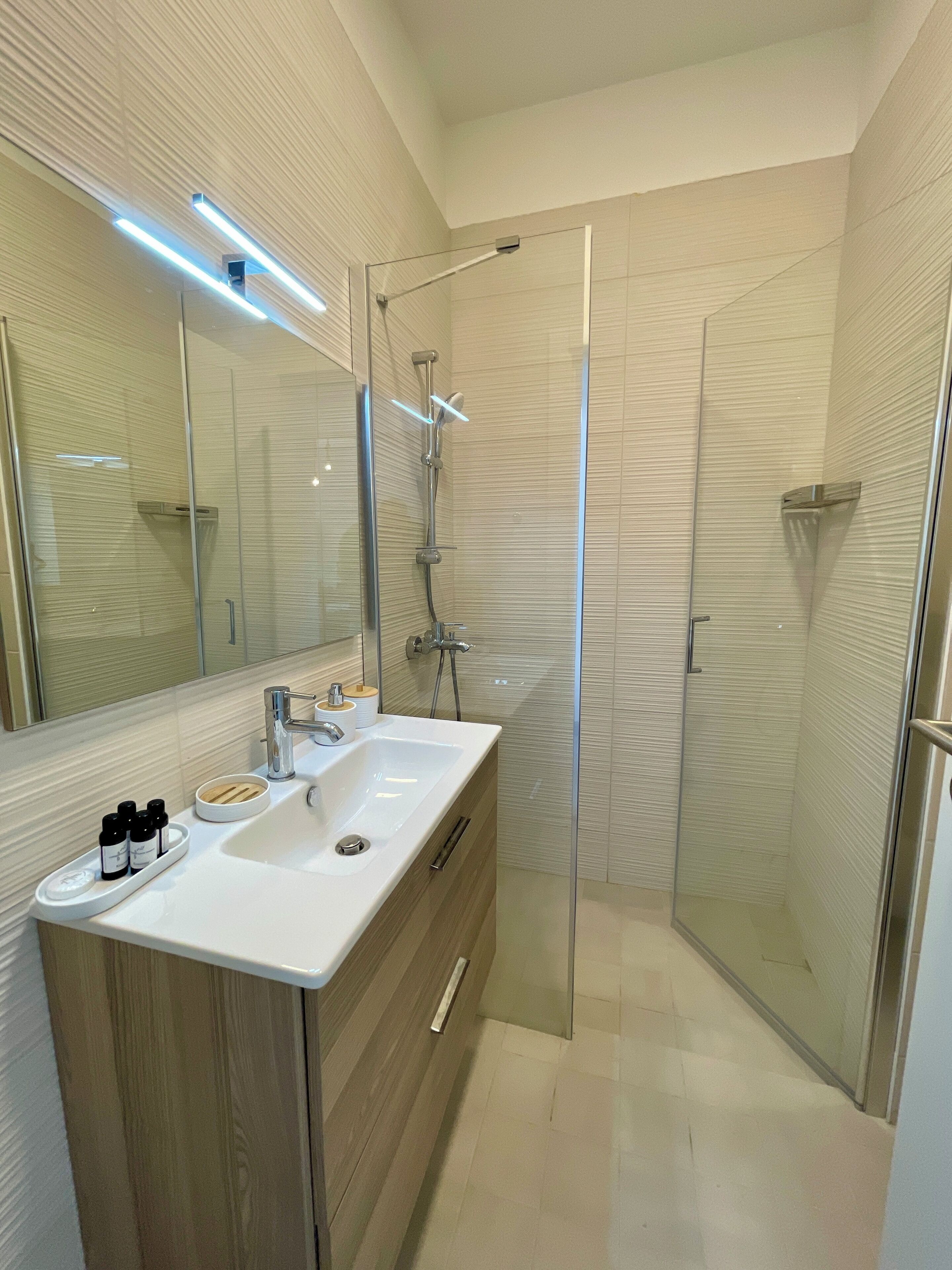 A modern bathroom with a glass-enclosed shower, a vanity with a sink, and a mirror above it.