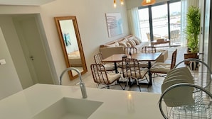 A modern kitchen with a large island, dining area with chairs, and a view of the outdoors. - Aladdin Chalets - 2.5 Bedrooms (Aqaba)