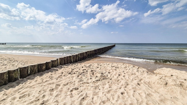 A beach with a wooden jetty extending into the ocean, sandy beach, and a clear sky with clouds. - 2 bedroom amazing home in Dziwnówek (Dziwnówek)