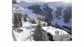 Un complejo turístico en la montaña cubierto de nieve, con edificios modernos y pistas de esquí.