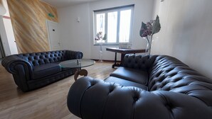 Ein modernes Wohnzimmer mit einer schwarzen Ledersofa, einem Glastisch und Holzboden.