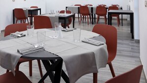 Ein moderner Konferenzraum mit Tischen und Stühlen, ausgestattet mit Gläsern und Servietten.