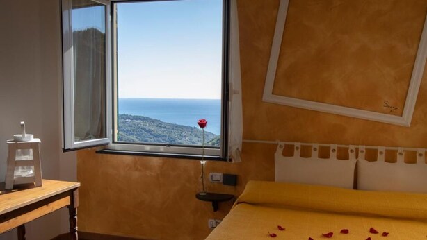 Ein Schlafzimmer mit großem Fenster und Meer- und Bergblick.