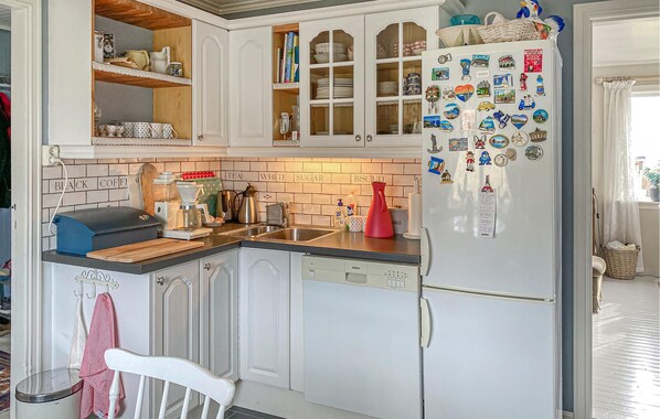 A kitchen with white cabinets, a Bosch dishwasher, and a refrigerator adorned with magnets.