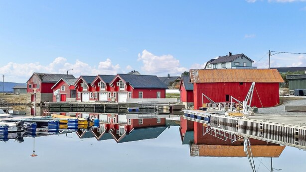A waterfront property with red buildings, a dock, and boats. - 3 bedroom cozy apartment in Myklebost (Myklebost)