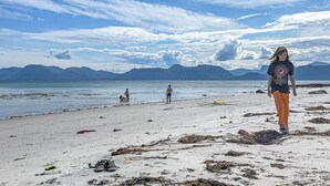 A beach with a clear sky, mountains in the background, and a few people. - 3 bedroom cozy apartment in Myklebost (Myklebost)