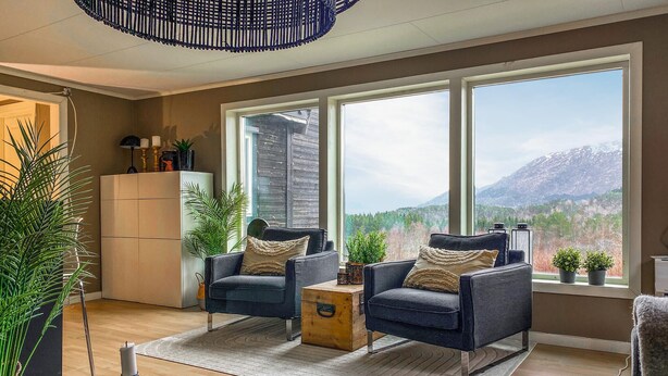 A living room with two armchairs, a wooden chest, and a large window with a mountain view. - Amazing apartment in Kvisvik (Kvisvik)