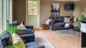 A modern living room with a grey sofa, a coffee table, and a small side table. There are potted plants and a rug on the floor. - Amazing apartment in Kvisvik (Kvisvik)