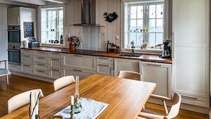 Eine moderne Küche mit Holztisch, weißen Schränken und einem großen Fenster.