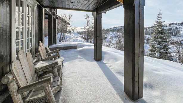 Eine hölzerne Veranda mit Blick auf eine verschneite Landschaft.