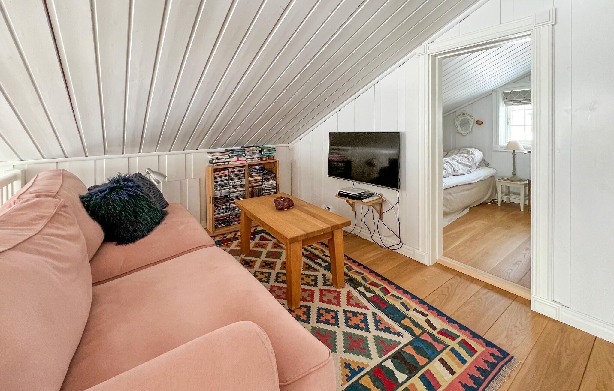 Ein gemütliches Wohnzimmer mit einer Couch, einem kleinen Holztisch, einem Fernseher und einem Bücherregal.