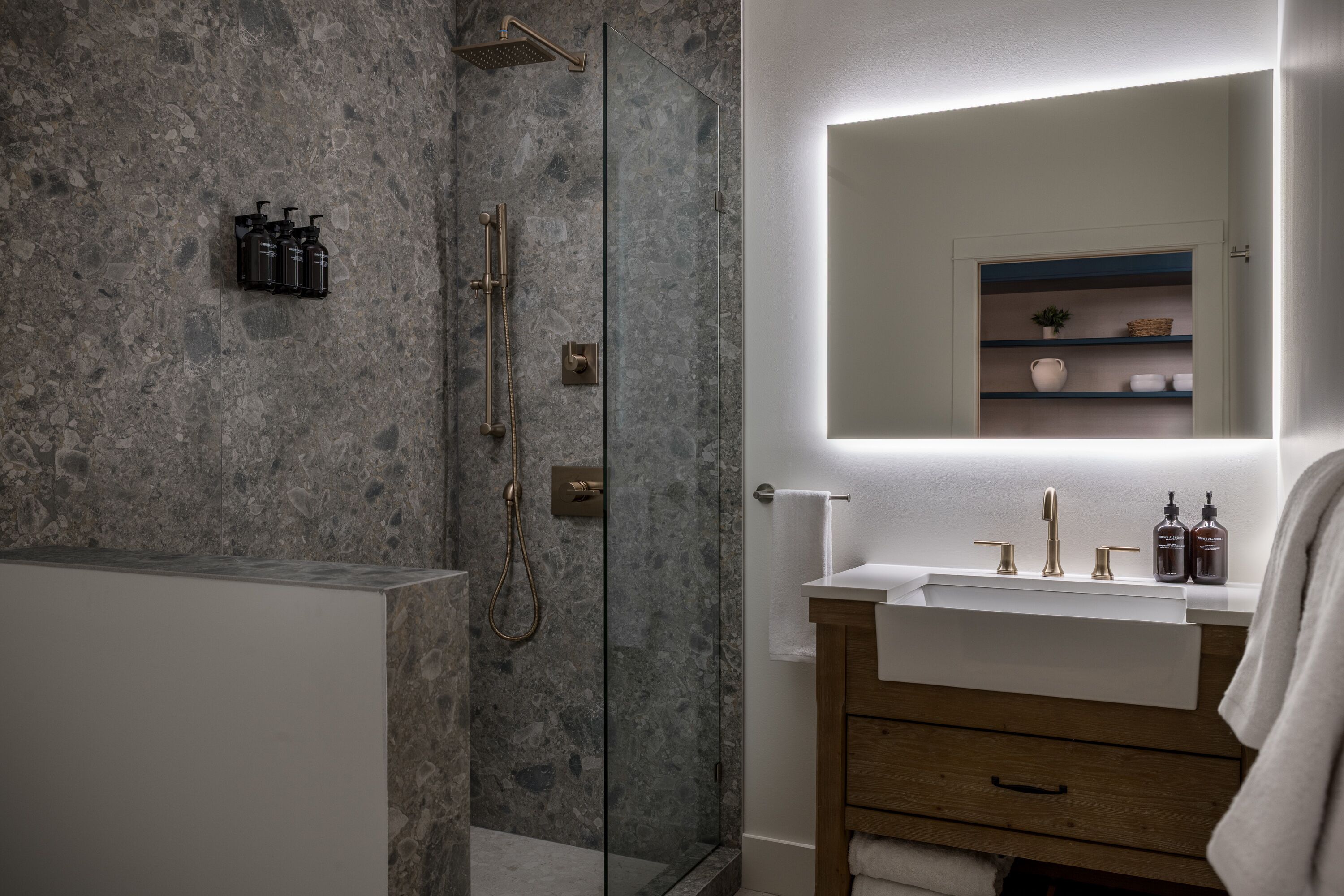Ein modernes Badezimmer mit einer gläsernen Duschkabine, einem Holzbadezimmer-Möbel und einem Spiegel über dem Waschbecken.