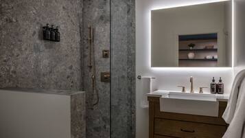 A modern bathroom with a glass-enclosed shower, a wooden vanity, and a mirror above the sink.