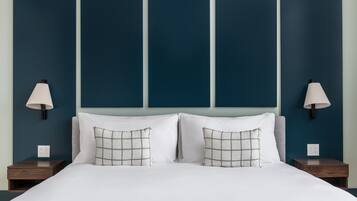 A neatly made bed with white linens and two pillows, flanked by two nightstands with lamps, against a wall with three vertical panels.