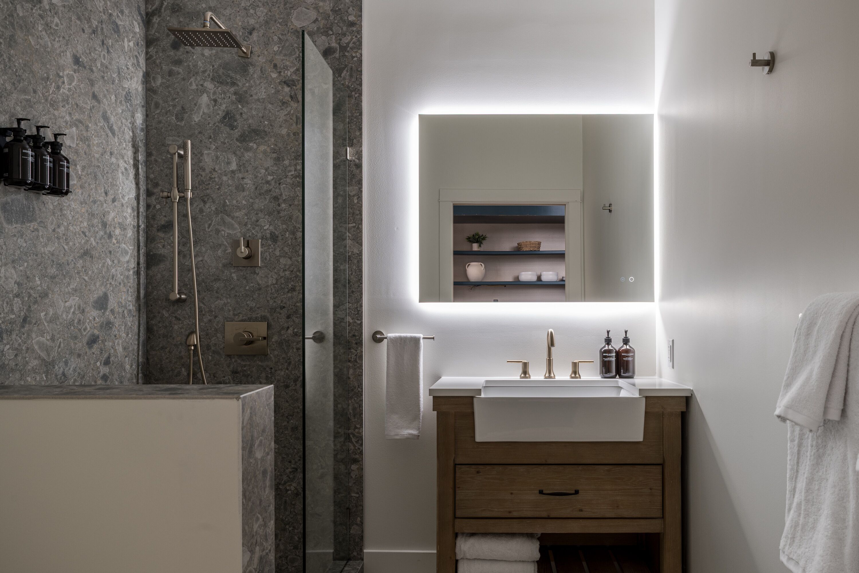 A modern bathroom with a shower, a vanity with a mirror, and a towel rack.