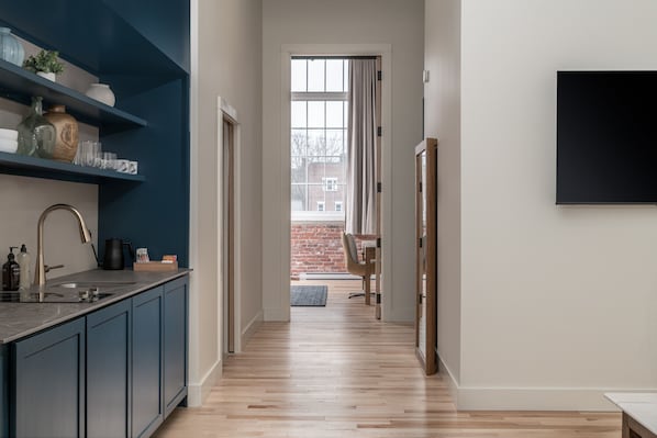 A modern kitchen with dark blue cabinets, a black countertop, and a window with curtains.