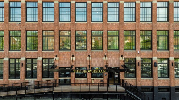 Un edificio de ladrillo de varios pisos con una entrada central que dice "The Skowhegan".