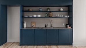 Una cocina moderna con armarios azul oscuro, una encimera de madera y un estante empotrado con utensilios de cocina y una pequeña planta en maceta.