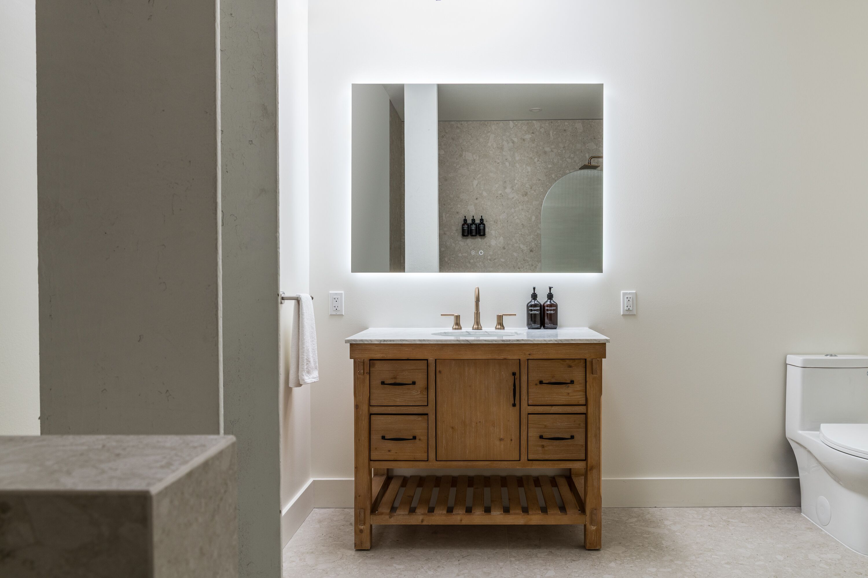 Un baño con tocador de madera, un espejo grande y un inodoro.