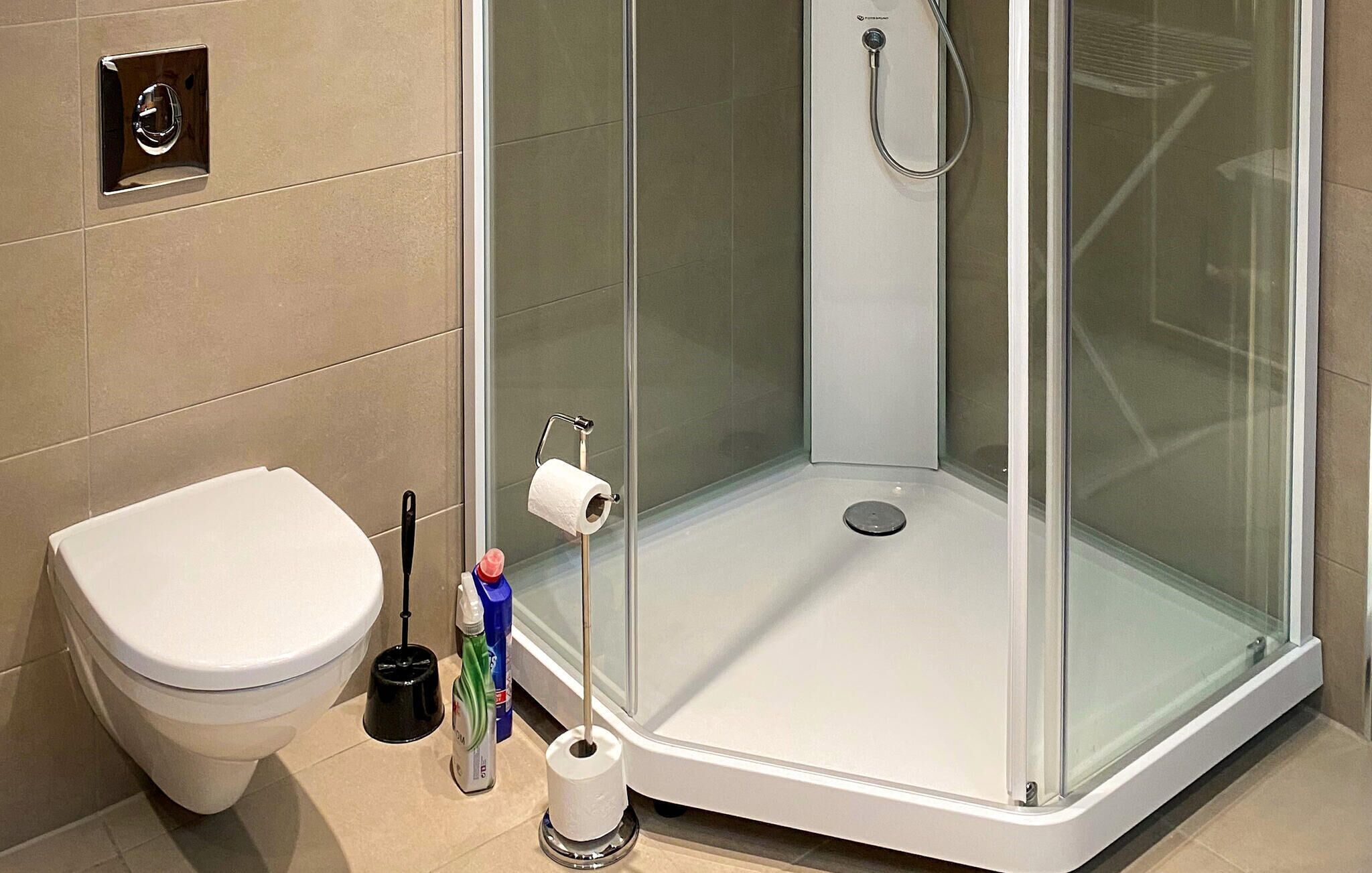 A modern bathroom with a glass-enclosed shower, a toilet, and a sink.