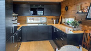 Une cuisine moderne avec des meubles de couleur sombre, un plan de travail en bois et une grande fenêtre.