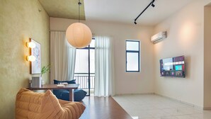 A modern living room with a bean bag chair, a dining table, a TV, and a large window. - The Sun by Stellar ALV (George Town)