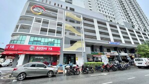 A modern building with a sushi restaurant on the ground floor, a parking area with motorcycles, and a tall residential building in the background. - The Sun by Stellar ALV (George Town)