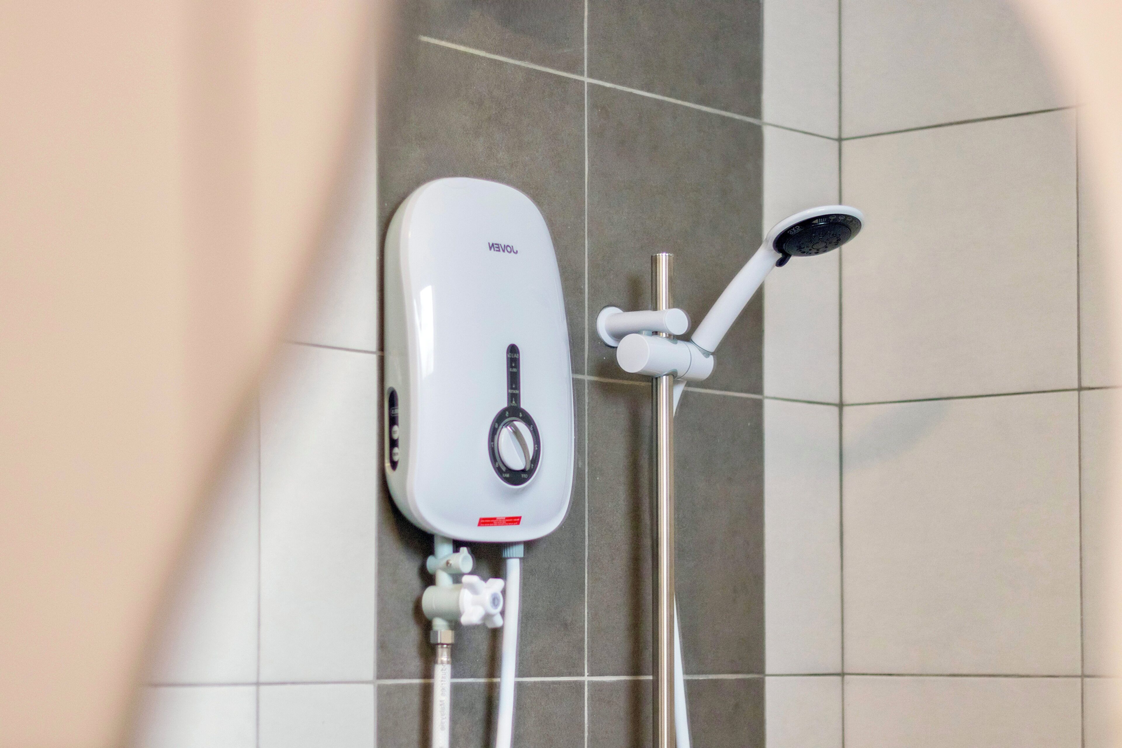 A wall-mounted shower unit with a control panel and a handheld showerhead.